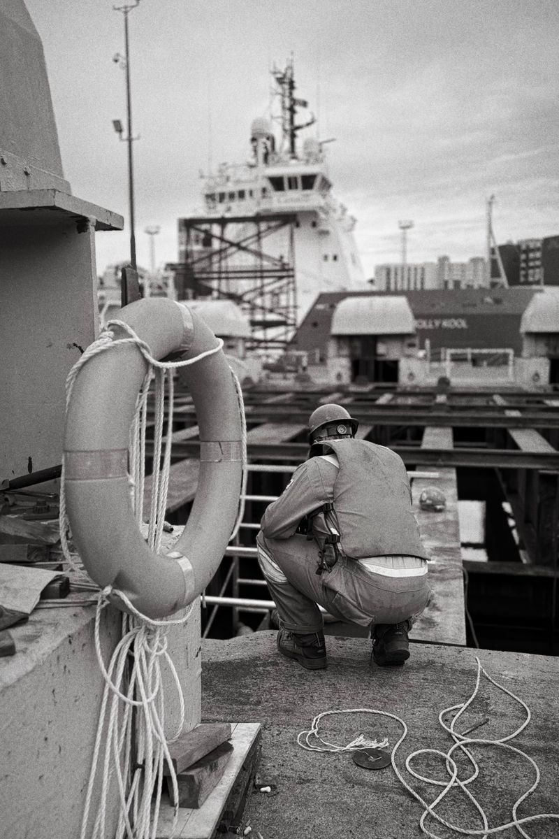 A dock worker inspecting a ship in a dockyard