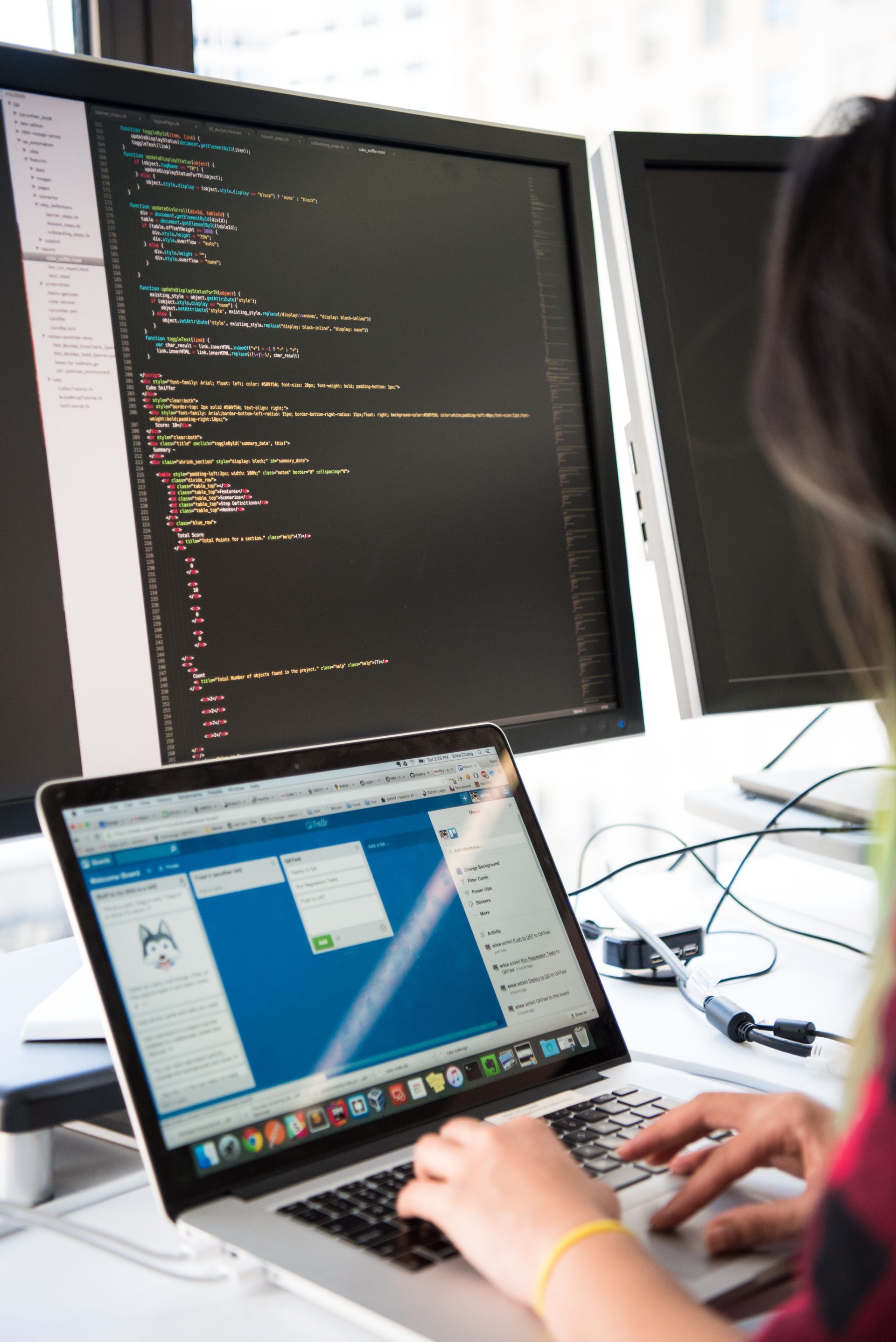 A developer working across multiple screens and a laptop
