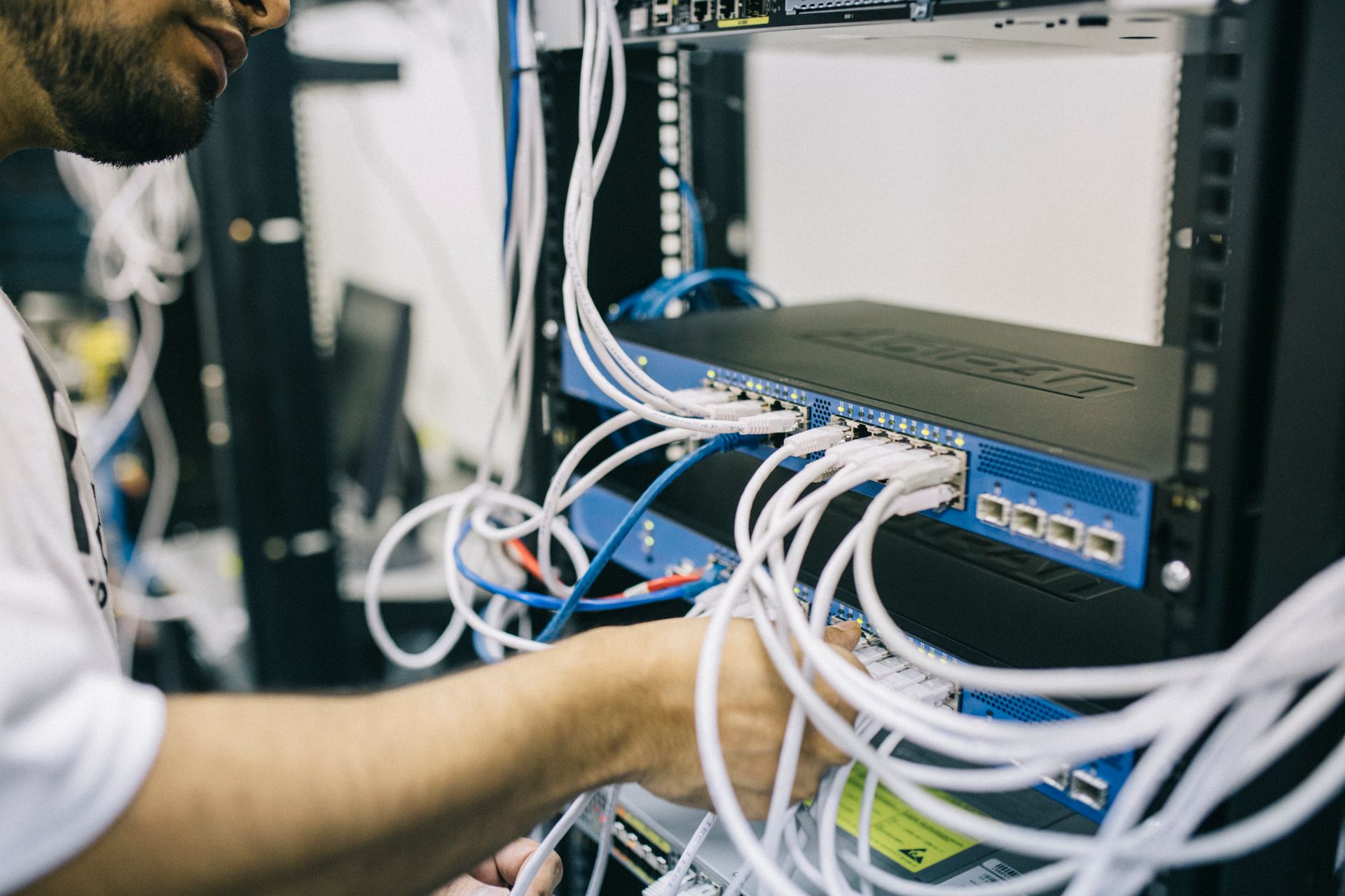 An IT professional configuring network cables in a server rack