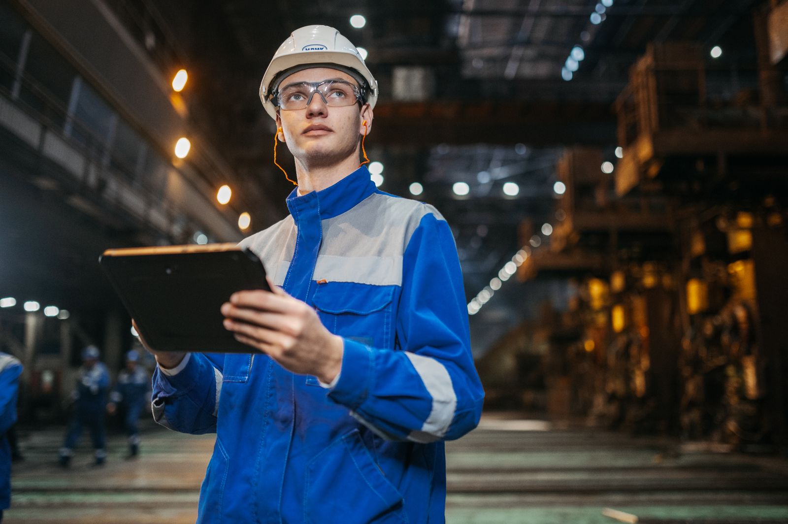 An engineer using a tablet on a modern factory floor