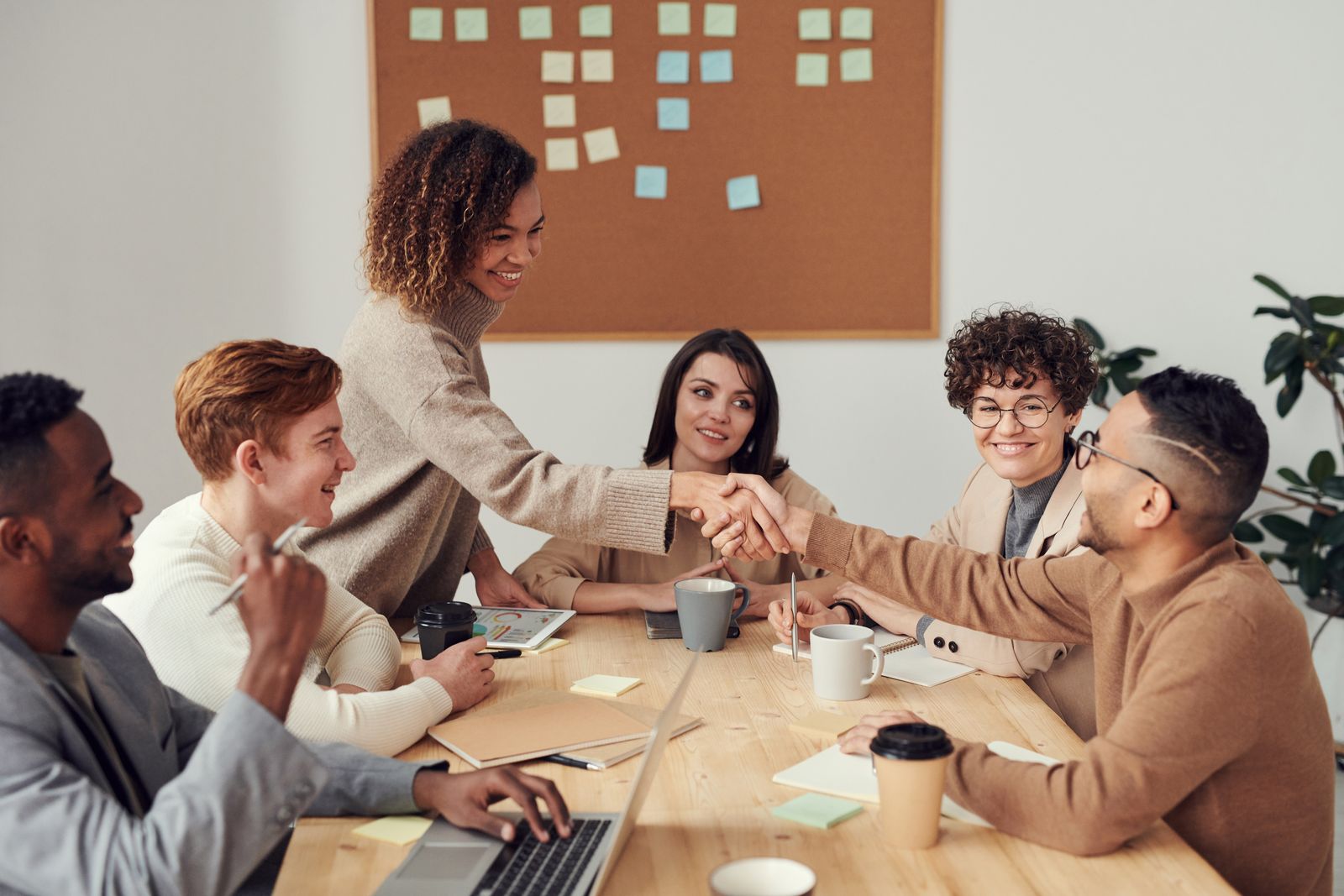 Two teams shaking hands across a meeting table