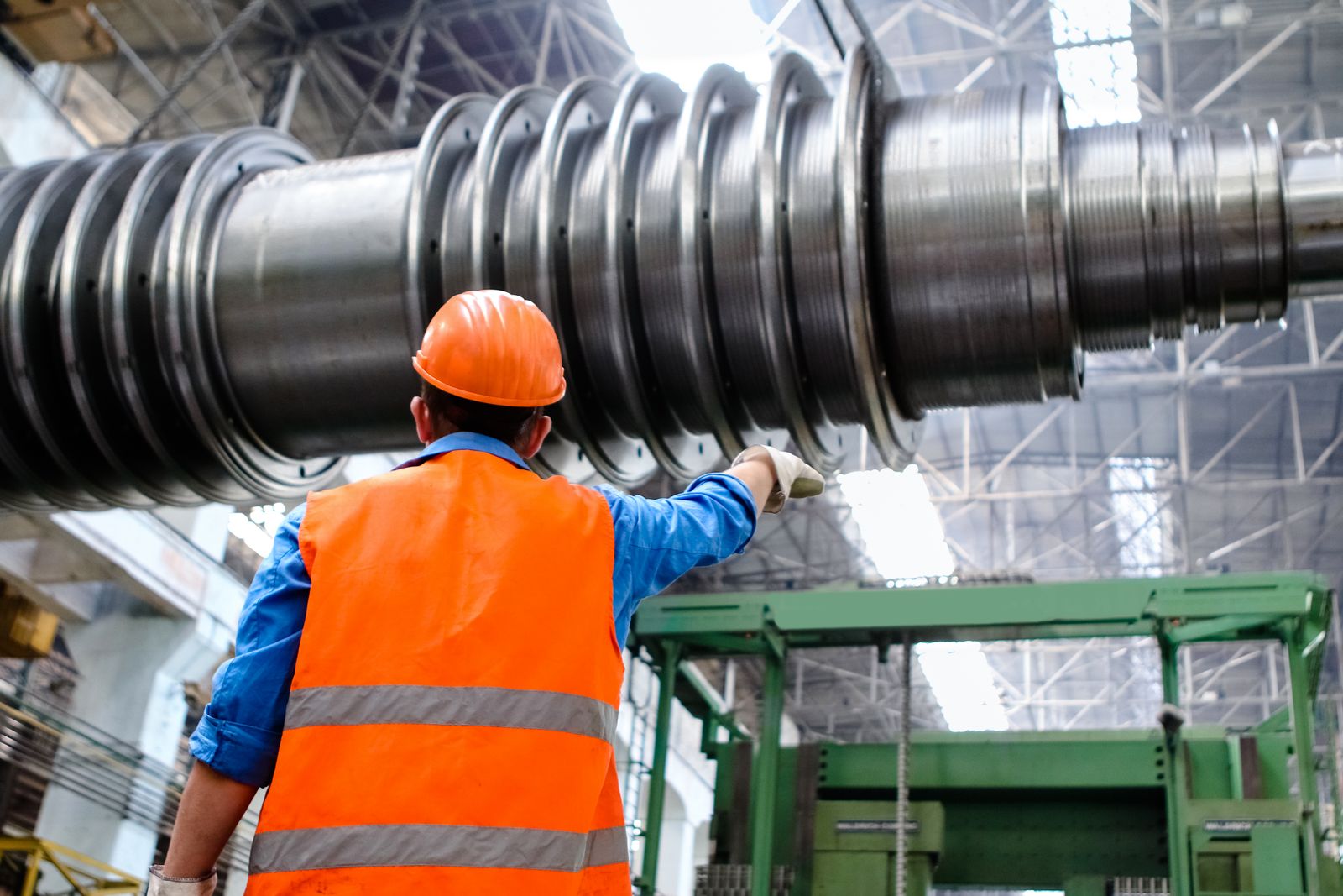An engineer in high-visibility gear inspecting turbine machinery