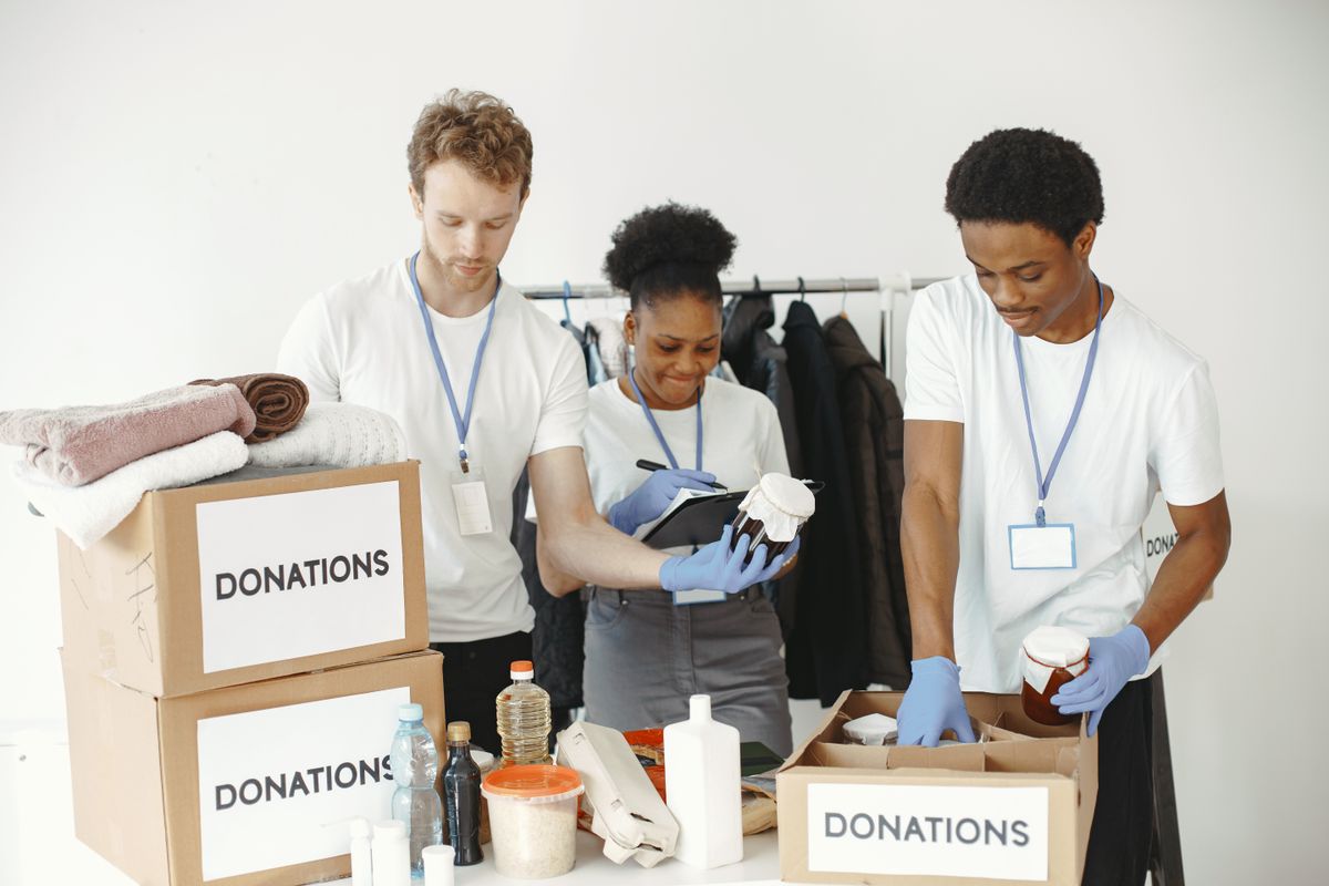 Three volunteers organizing donation boxes in a community center